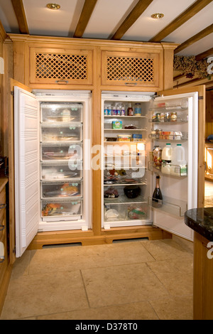 Well stocked fridge freezer in an upmarket solid wood fitted kitchen. Stock Photo