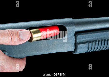 A man loads a red shotgun shell into the chamber of a pump action rifle. Stock Photo