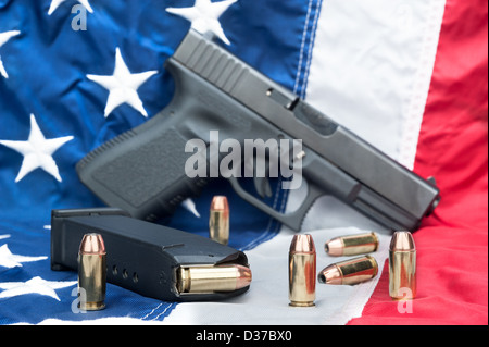 A handgun with a full magazine and scattered bullets on an American flag. Stock Photo