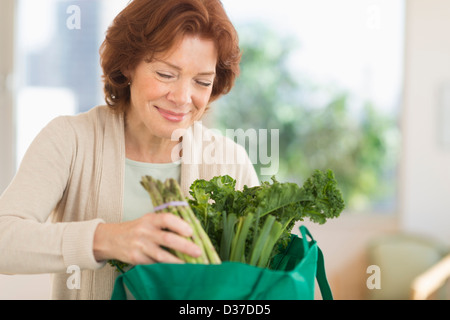 USA, New Jersey, Jersey City, Senior woman with groceries in kitchen Stock Photo