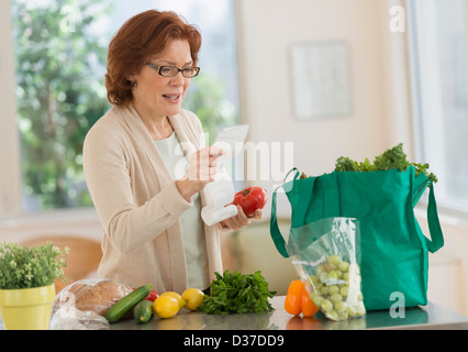 USA, New Jersey, Jersey City, Woman reading shopping list in kitchen Stock Photo