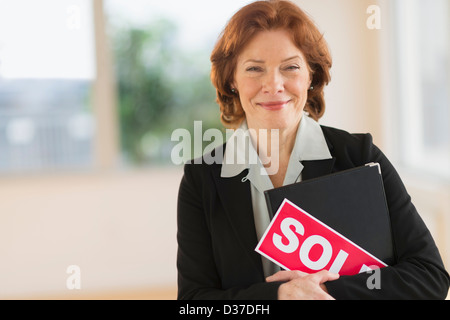 USA, New Jersey, Jersey City, Portrait of female real estate agent holding sold sign Stock Photo