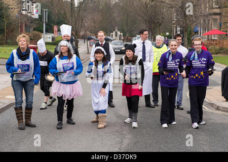 Competitors lining up at start, taking part & about to run in traditional, annual Ilkley Rotary Pancake Race - The Grove, Ilkley, West Yorkshire, UK. Stock Photo