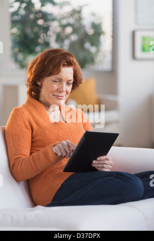 USA, New Jersey, Jersey City, Woman sitting on sofa using digital tablet Stock Photo
