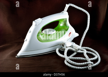 The electric iron stands on a brown background Stock Photo
