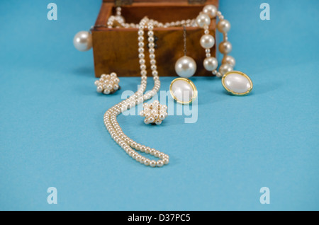 pearl jewelry beads necklace earring in retro wooden box on blue background. Stock Photo