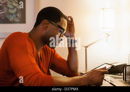 Man using tablet computer at desk Stock Photo