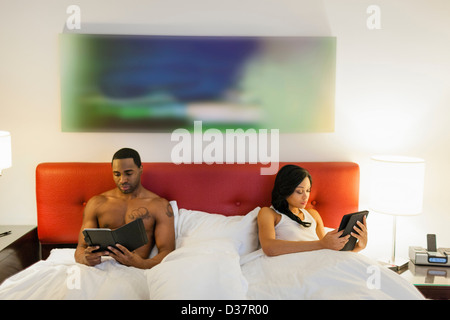 Couple using e-readers in bed Stock Photo
