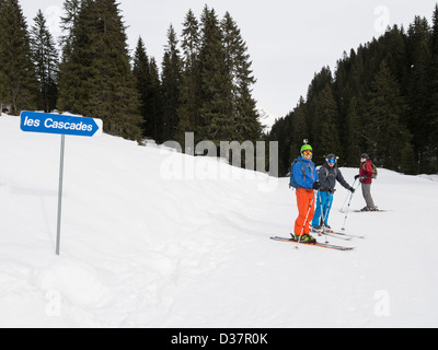 Skiers by sign on les Cascades blue ski slope to Sixt in Le Grand Massif skiing area near Samoens, Rhone-Alpes, France Stock Photo