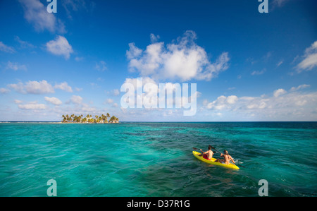 People rowing canoe in tropical water Stock Photo