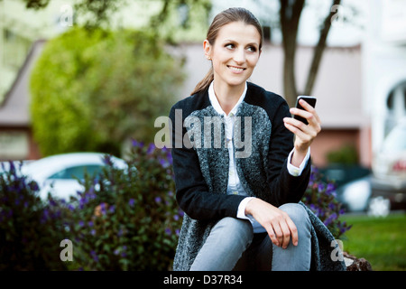 Woman using cell phone in urban park Stock Photo