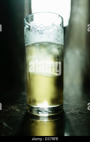Glass of beer illuminated on bar Stock Photo