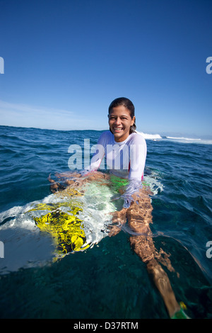 Girl sitting on surfboard in water Stock Photo