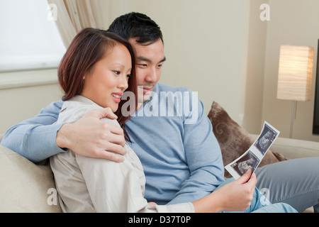 Couple examining sonogram on sofa Stock Photo