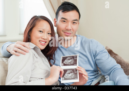 Couple displaying sonogram on sofa Stock Photo