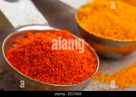 Dired curcuma and paprika spices in metal scoops on wooden table Stock Photo