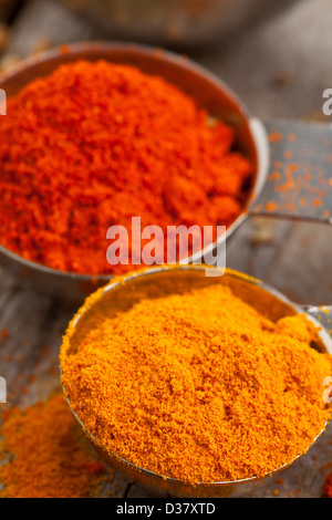 Dired curcuma and paprika spices in metal scoops on wooden table Stock Photo