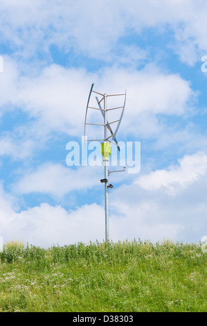 small vertical axis wind turbine on a green hill Stock Photo