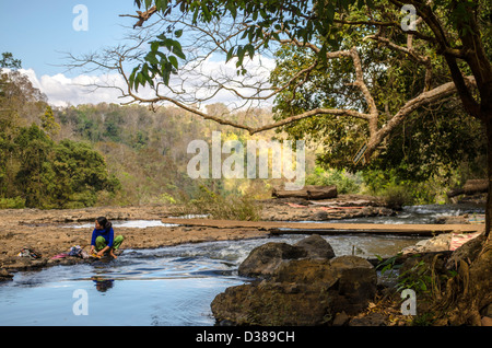 Indigenous woman washing clothes in river at Bou Sra Waterfall in Mondulkiri Cambodia Stock Photo