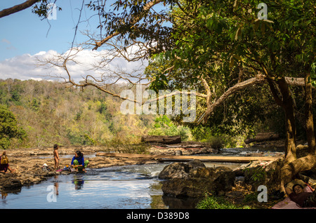 Indigenous woman washing clothes in river at Bou Sra Waterfall in Mondulkiri Cambodia Stock Photo