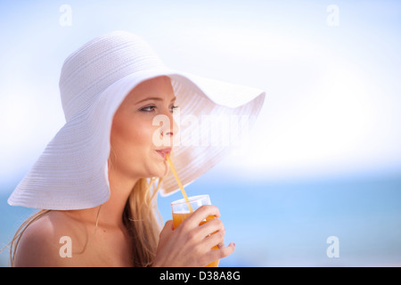 Woman in floppy hat drinking juice Stock Photo