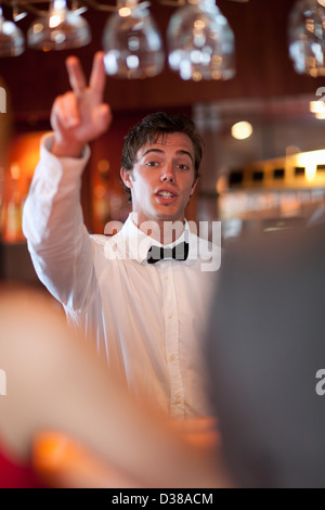 Waiter offering more drinks at bar Stock Photo