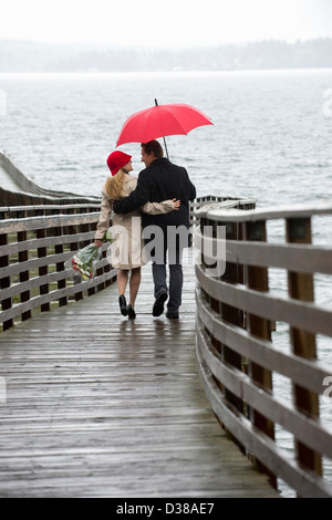 Couple walking on wooden pier in rain Stock Photo