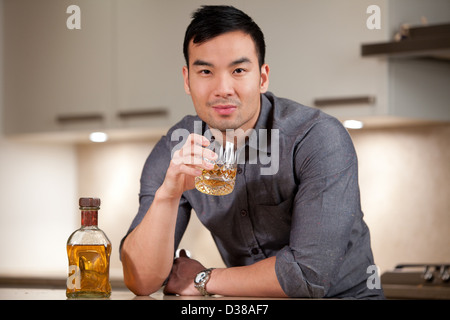 Man having glass of whiskey in kitchen Stock Photo