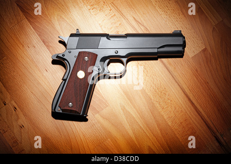 Semi-automatic M1911 Mark IV Series 80 .45 caliber pistol on the wooden table. Stock Photo