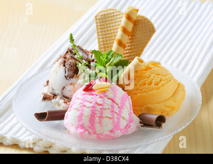 Three scoops of ice cream garnished with wafers and herbs Stock Photo