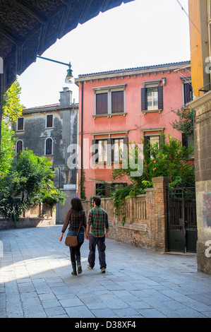 Two People Walking through Archway on the Calle di Mezzo in Venice Stock Photo