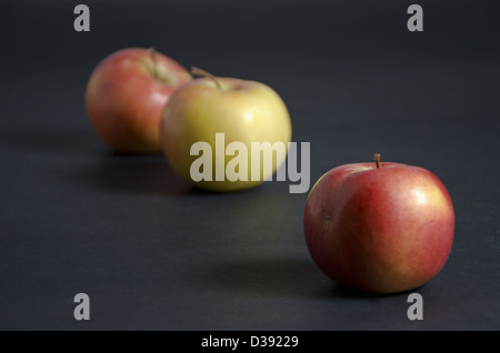 Three apples on dark background, first in focus Stock Photo