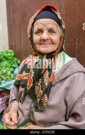Old Berber woman with face tattoos selling vegetables in the Medina, Fes, Morocco Stock Photo