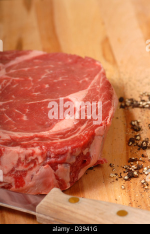 A rib eye steak with cracked black pepper and a knife Stock Photo