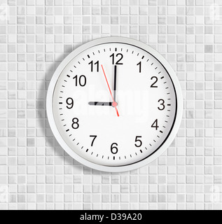 Simple clock or watch on white tile wall displaying nine o'clock Stock Photo