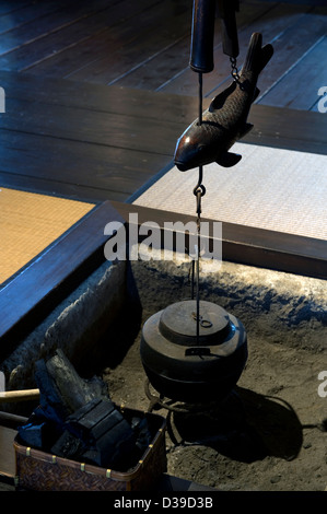 An irori, or sunken hearth fire pit, with jizaikagi, or bamboo tube and wooden fish kettle holder, found in traditional homes. Stock Photo