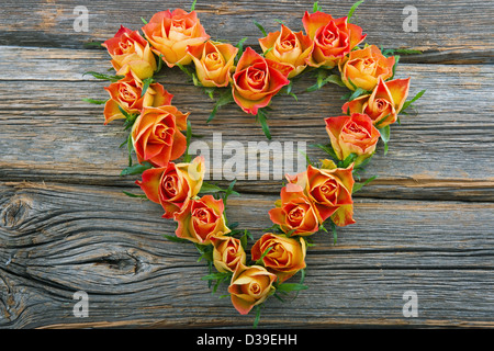 Orange roses in heart shape on wooden background Stock Photo