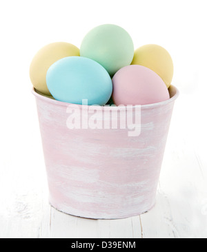 Easter eggs in pink decorative bucket on white wooden background Stock Photo