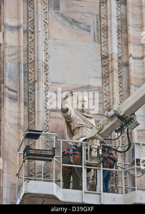 Workers on hydraulic platform restoring a statue sculpture artwork on facade Milan Cathedral Milano Lombardy Italy Europe Stock Photo