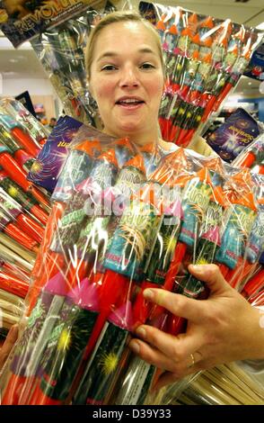 (dpa) -  Sales assistant Annette Mueller smiles as she holds bags of fireworks and rockets in her hands at a department store in Frankfurt, Germany, 29 December 2003. Two days ahead of New Year's Eve customers are preparing themselves to welcome the new year with plenty of fireworks and drinks. Stock Photo