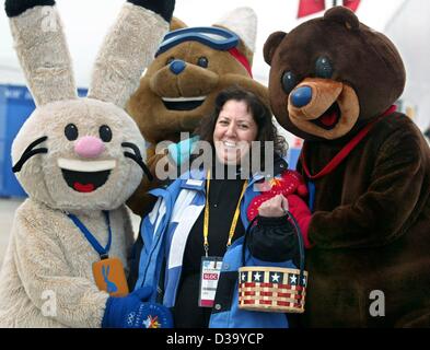 (dpa) - XIX Winter Olympic Games: The three Olympic mascots, (l-r) rabbit 'Powder', coyote 'Copper' and bear 'Coal', caress voluntary helper Dessie Manoussa during the speed skating competition at the Utah Olympic Oval in Salt Lake City, 14.2.2002. Dessie is one of the 22000 voluntary helpers workin Stock Photo