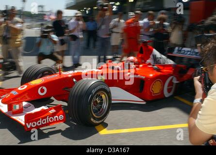 (dpa) - Michael Schumacher, German formula 1 champion, drives his new Ferrari F2002 in front of numerous photographers onto the racing track in Interlagos near Sao Paulo, 29 March 2002. Stock Photo