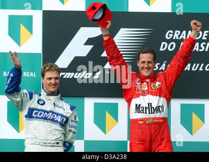 (dpa) - German Formula One driver Michael Schumacher (r) raises his arms celebrating his victory in the 2002 Brazilian F1 Grand Prix , 31 March 2002, in Sao Paulo. Next to him on the podium his brother Ralf Schumacher (l) who came second. Stock Photo