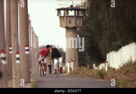 (dpa files) - A couple cycling on their bicycles are kissing as they cycle on the border roadway along the former wall in Berlin, in April 1990. Stock Photo