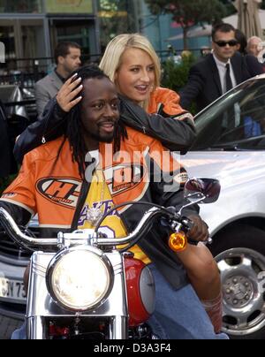 (dpa) - Haitian singer Wyclef Jean and German pop star Sarah Connor arrive together with his motorbike to the European premiere of the film 'Men In Black II' at the Sony-Center in Berlin, 11 July 2002. Stock Photo