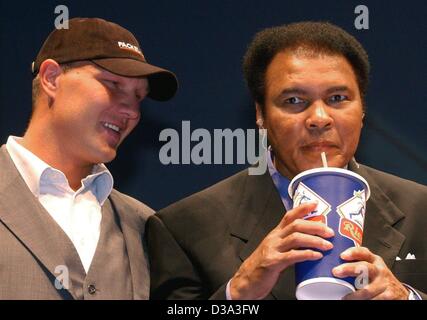 (dpa) - Boxing legend Muhammad Ali (R) drinks a milk shake offered by German ex boxer Axel Schulz (L), in the arena of Riesa, east Germany, 28 June 2002. The former heavy-weight champion pays a visit to Germany on the occasion of the German premiere of his biographic film 'Ali'. Stock Photo