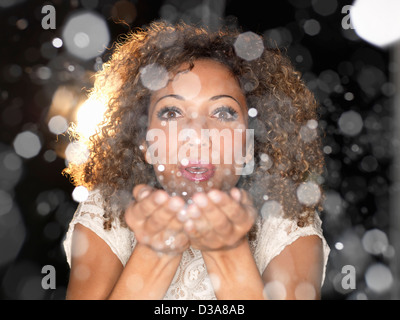 Woman blowing confetti from hands Stock Photo