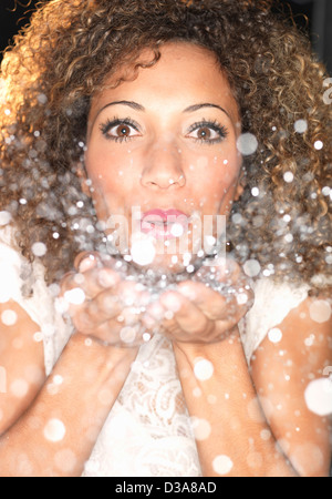 Woman blowing confetti from hands Stock Photo