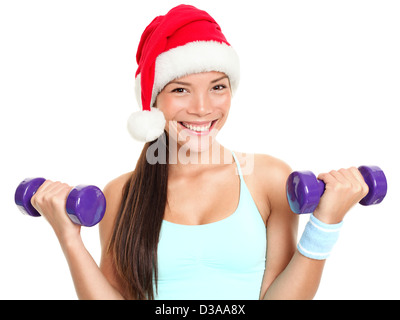 Portrait of happy mixed race young female fitness model woman wearing Santa hat lifting dumbbells isolated on white background Stock Photo