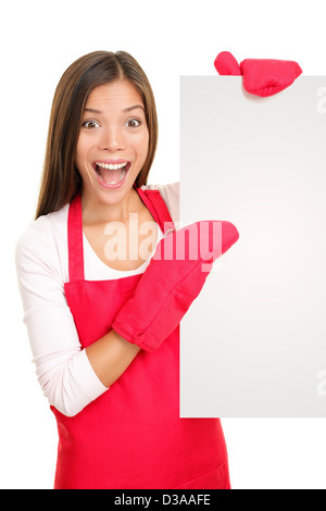 Portrait of excited happy young mixed race Chinese Asian / Caucasian woman showing sign wearing cooking mittens and red apron Stock Photo